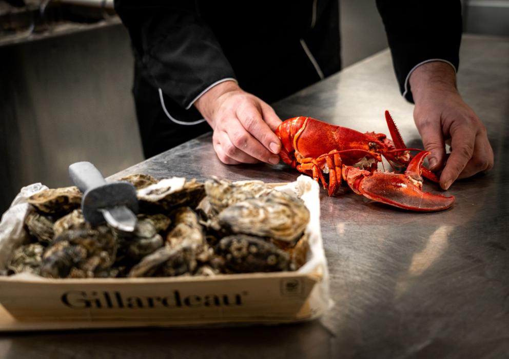 Chef al lavoro nella cucina del Ristorante Fuor d'Acqua: prepara con cura un'aragosta, simbolo della freschezza e della qualità dei nostri ingredienti. In primo piano, ostriche fresche, pronte per essere gustate